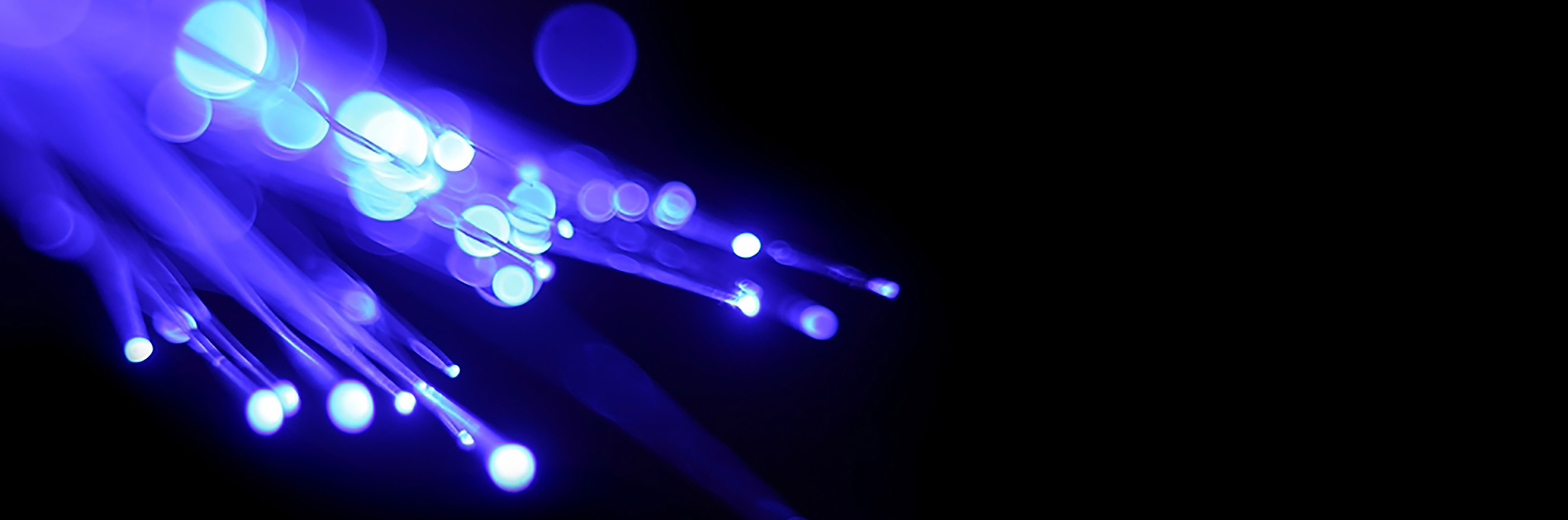 fiber optic cables glowing bright blue and white against a black background